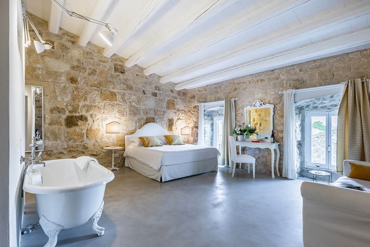  Udobna spavaća soba sa kamenim zidovima i belim nameštajem