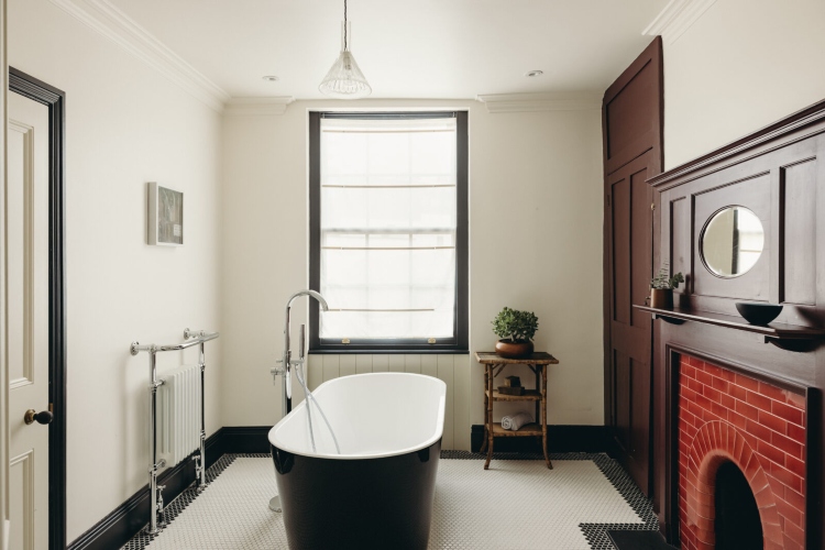  Kupatilo opremljeno u tradicionalnom stilu sa crno-belom samostojećom kadom