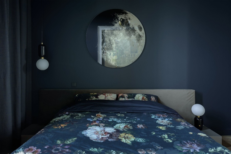  Spavaća soba sa tamno plavim zidovima i velikim okruglim ogledalom