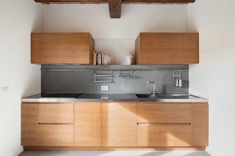  Kuhinja sa belim zidovima i drvenim ormarićima postavljenim na samo jednom zidu