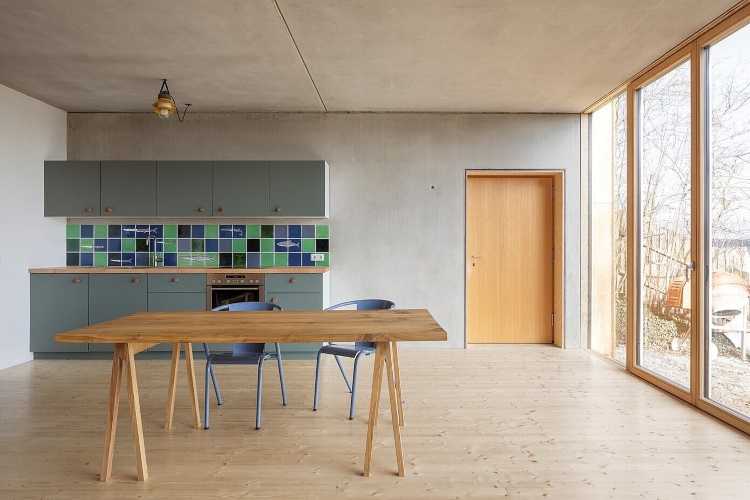  Minimalistički opremljena kuhinja sa drvenim trpezarijskim stolom i plavim ormarićima