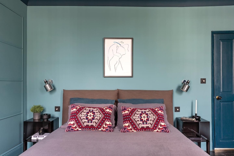  Kombinacija plavih zidova i ružičaste posteljine na krevetu stvara udoban i privlačan kutak za odmor