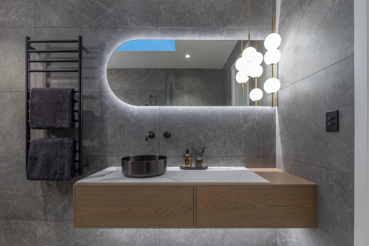  Zanimljiv dizajn ogledala i rasvete upotpunjuje izgled sivo-plavog kupatila