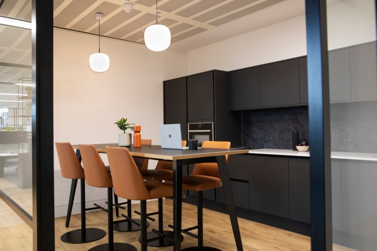  Kuhinja  sa crnim ormarićima i udobnim mestom za sedenje postaje zona za druženje zaposlenih