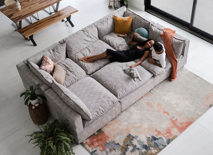 Udobna modularna sofa u sivoj boji ima mekane jastuke od perja