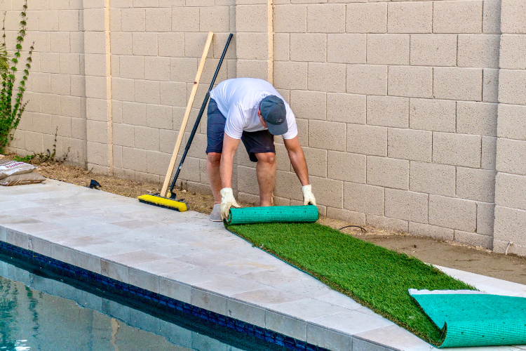 Čovek instalira veštačku travu pored ograde